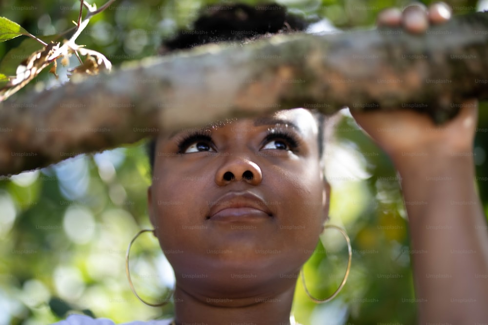 a woman is looking up at a tree branch