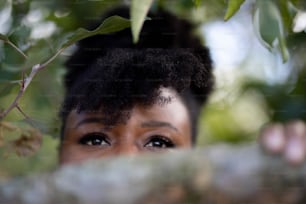 a close up of a person peeking out from behind a tree