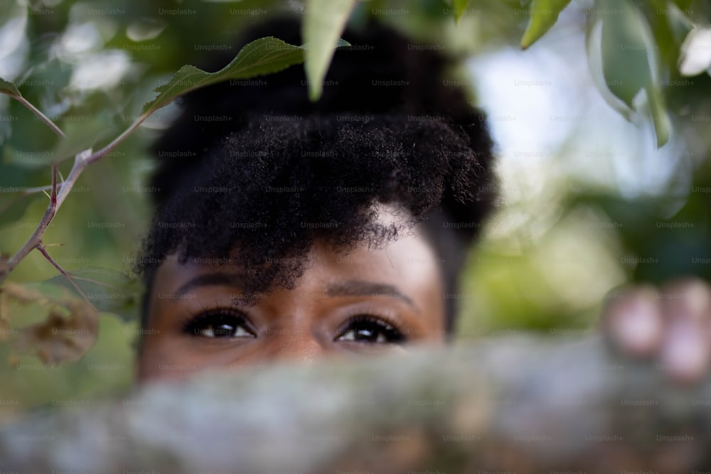 a close up of a person peeking out from behind a tree