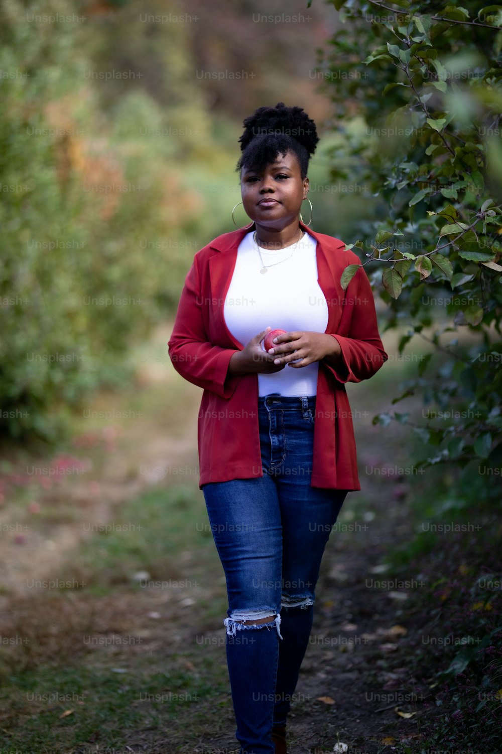 a woman in a red cardigan is walking down a path