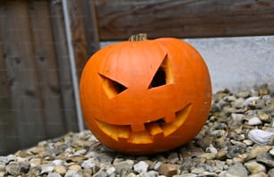 a carved pumpkin sitting on top of a pile of rocks