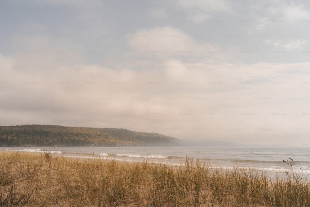 a sandy beach next to the ocean under a cloudy sky