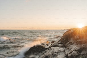una persona parada en una roca cerca del océano