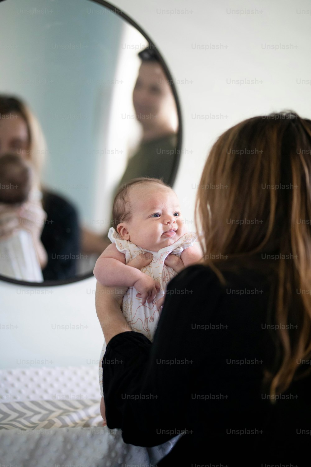 uma mulher segurando um bebê em frente a um espelho