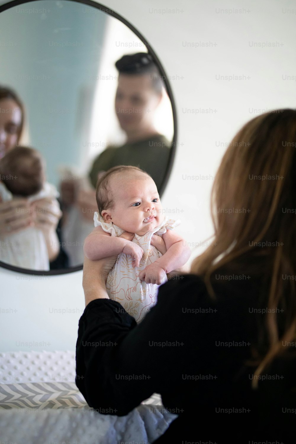 a woman holding a baby in front of a mirror