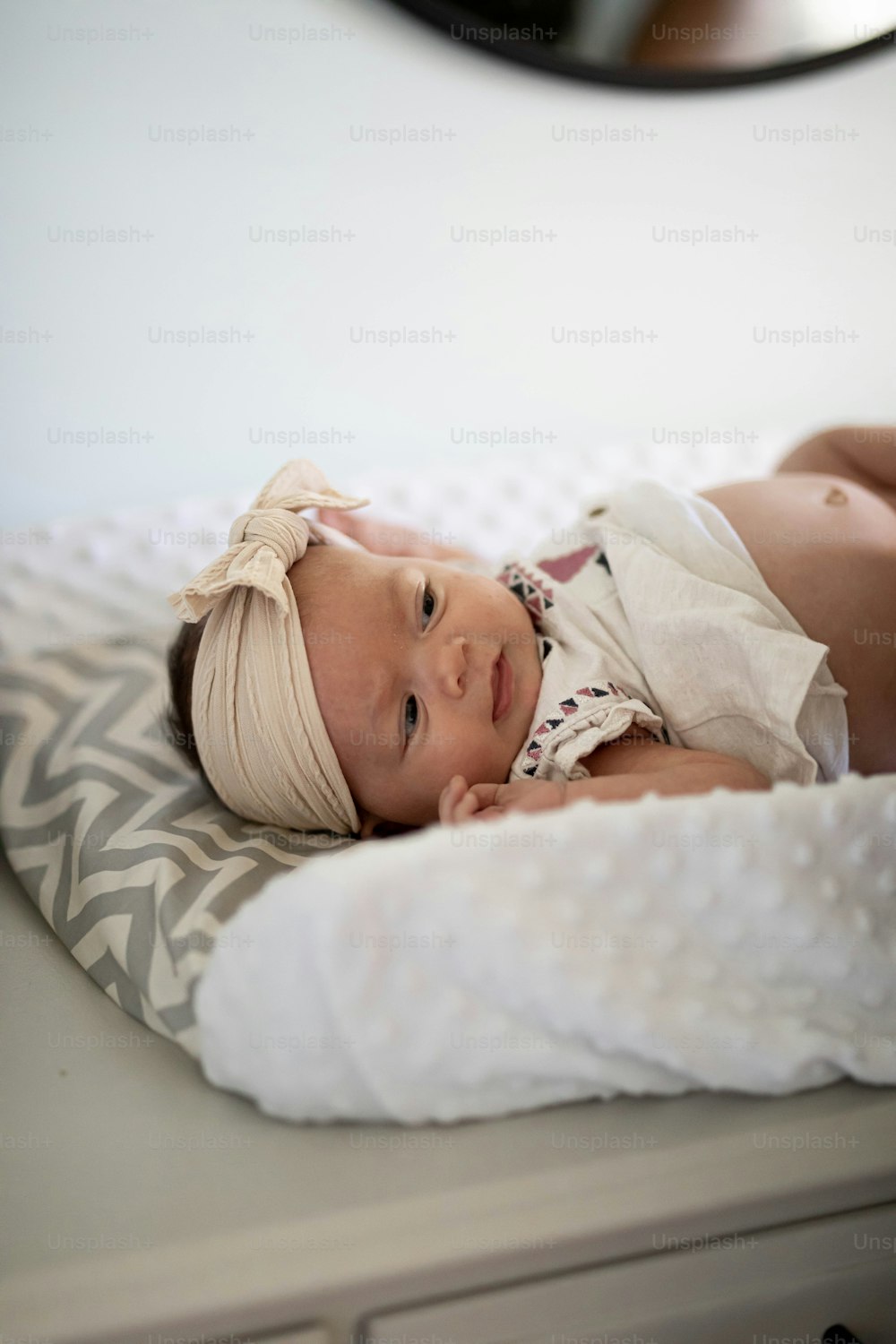 a baby laying on top of a bed next to a dresser