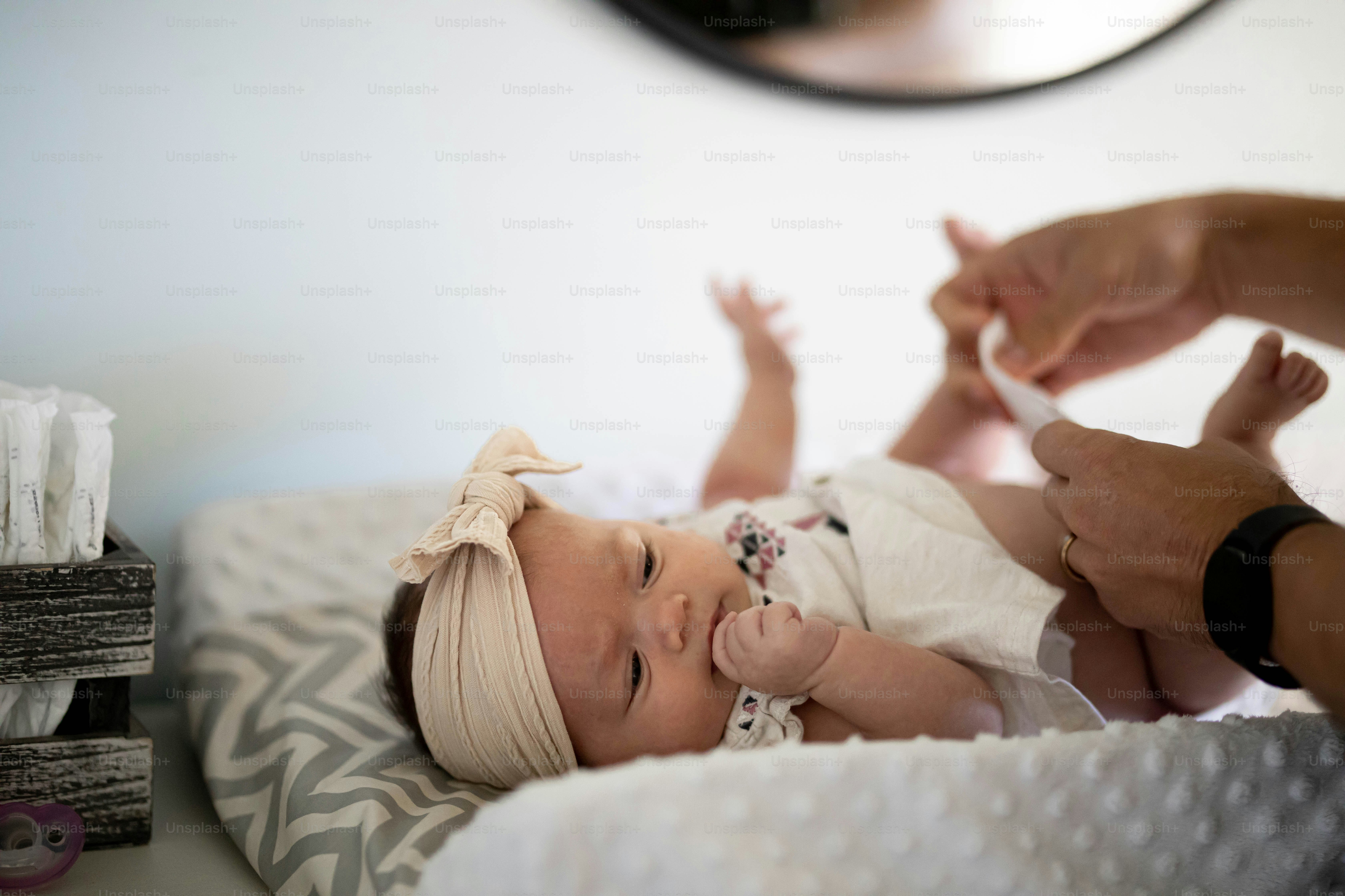 a baby laying on a bed being held by a person