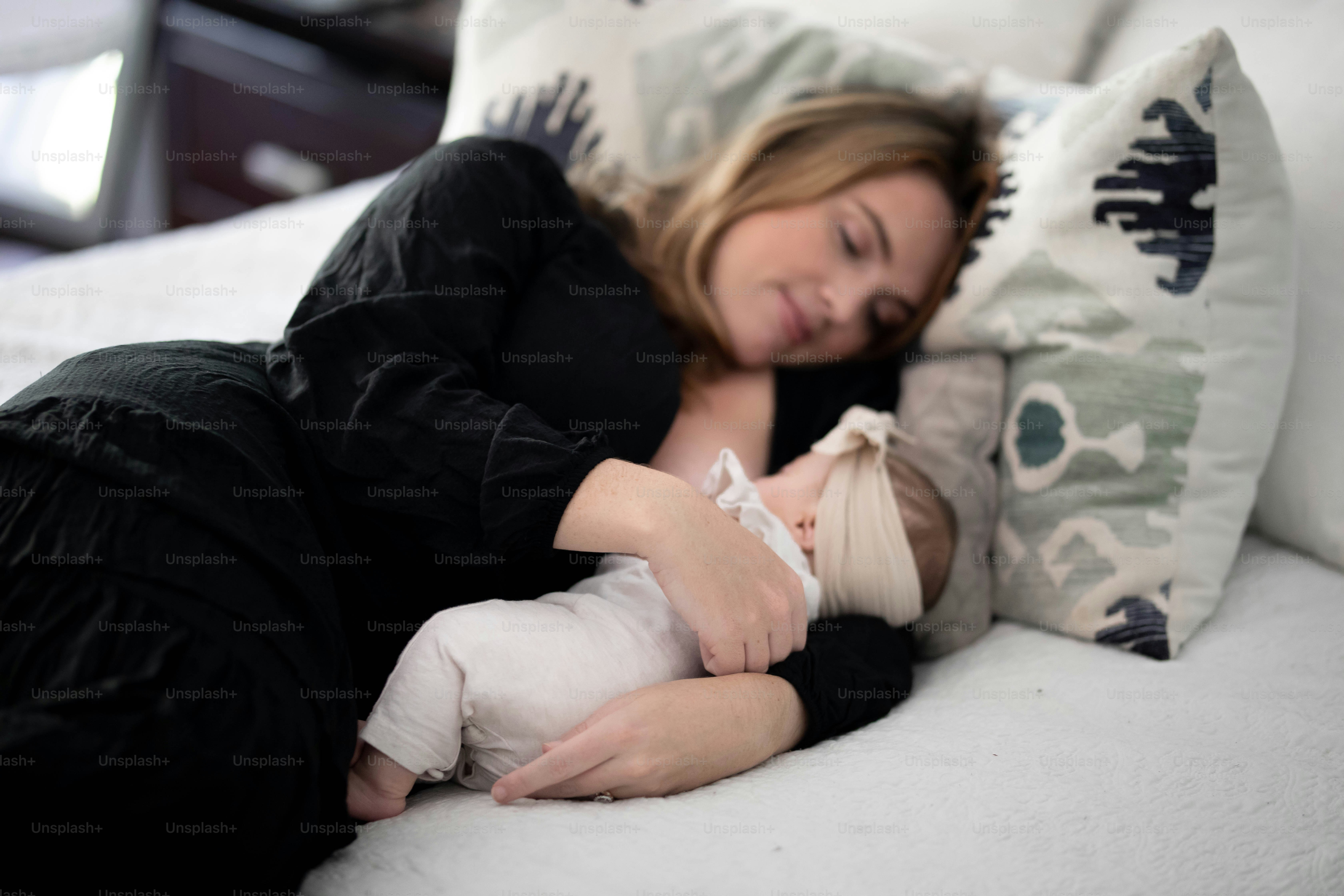 a woman laying on top of a bed holding a baby
