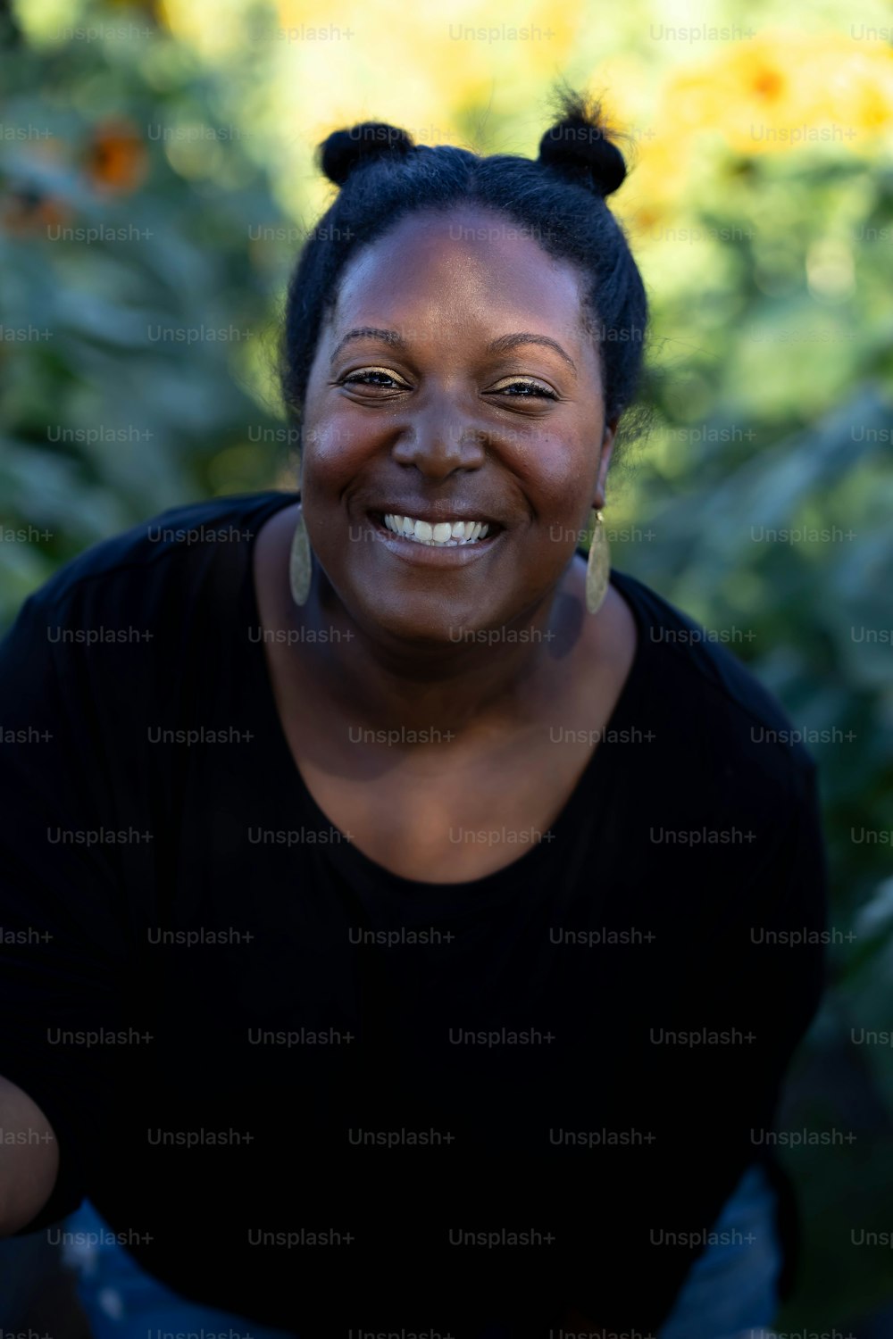 Una donna sorridente in una camicia nera in un campo di girasoli