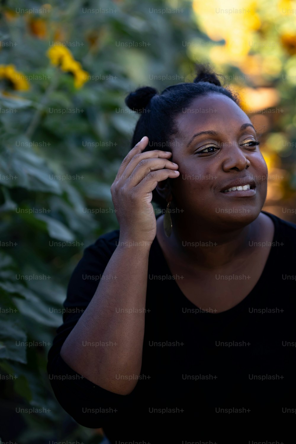 a woman talking on a cell phone in front of sunflowers