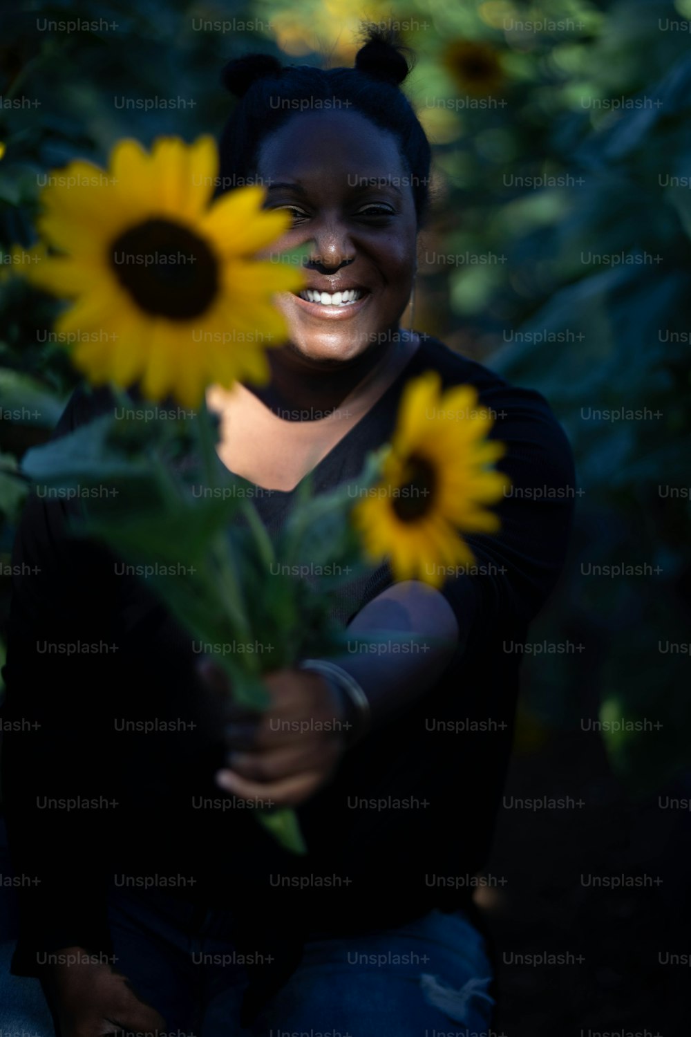 Une femme souriante tenant un bouquet de tournesols
