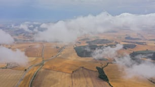 an aerial view of a farm land with clouds in the sky