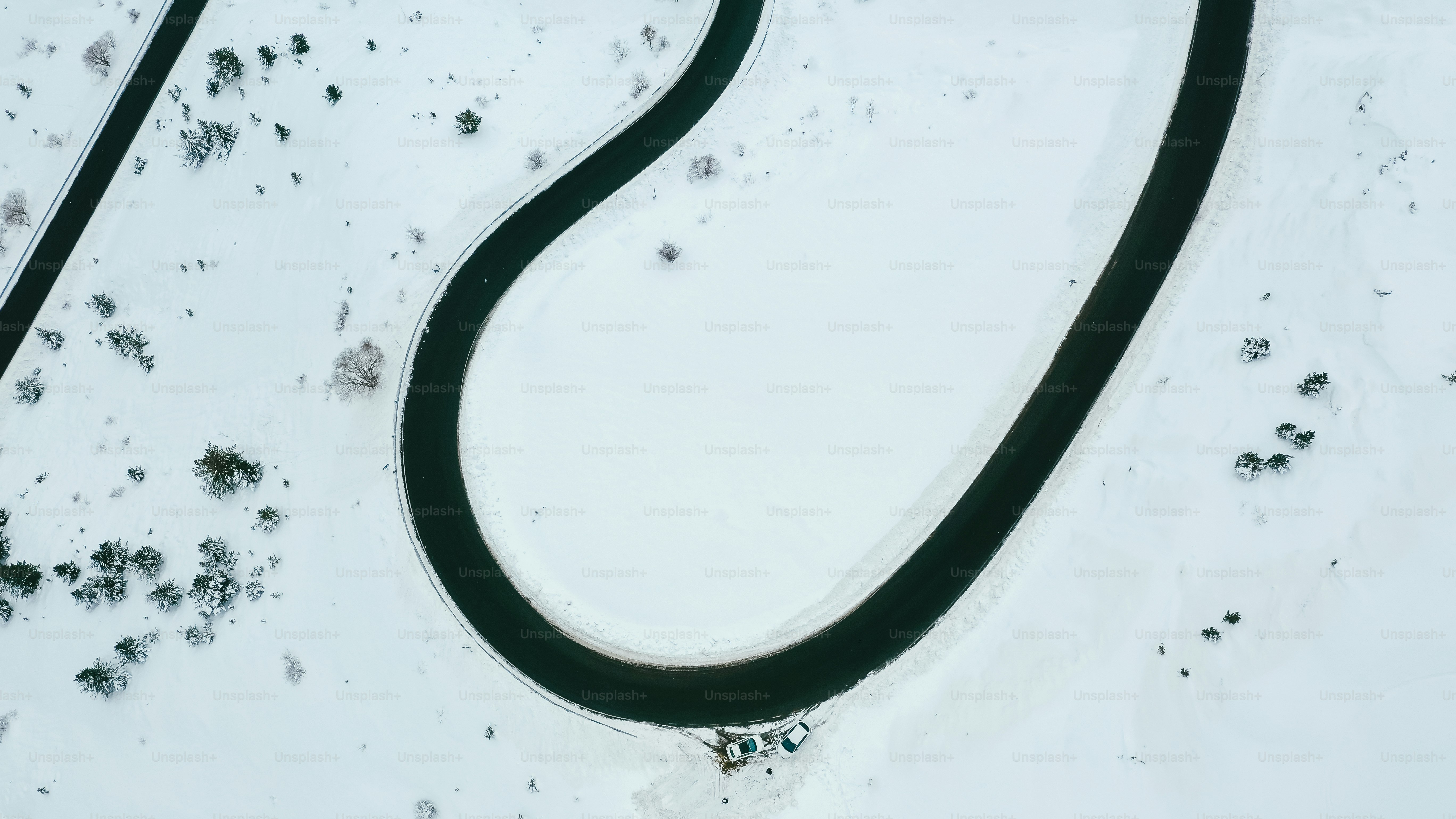 an aerial view of a winding road in the snow