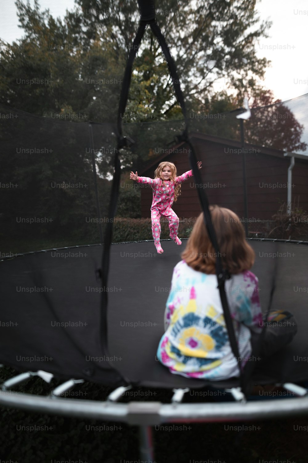 小さな女の子がトランポリンでジャンプしている