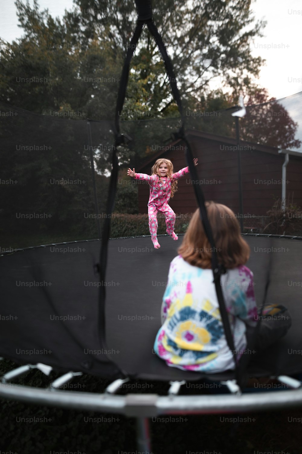 a little girl is jumping on a trampoline