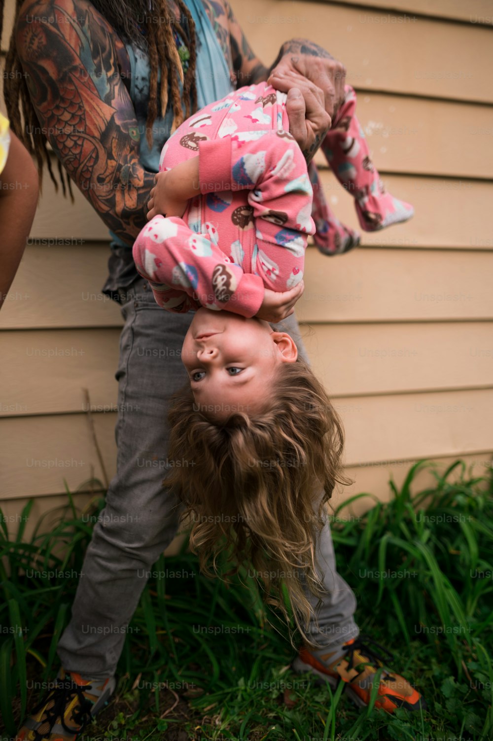 a man holding a child upside down in the grass