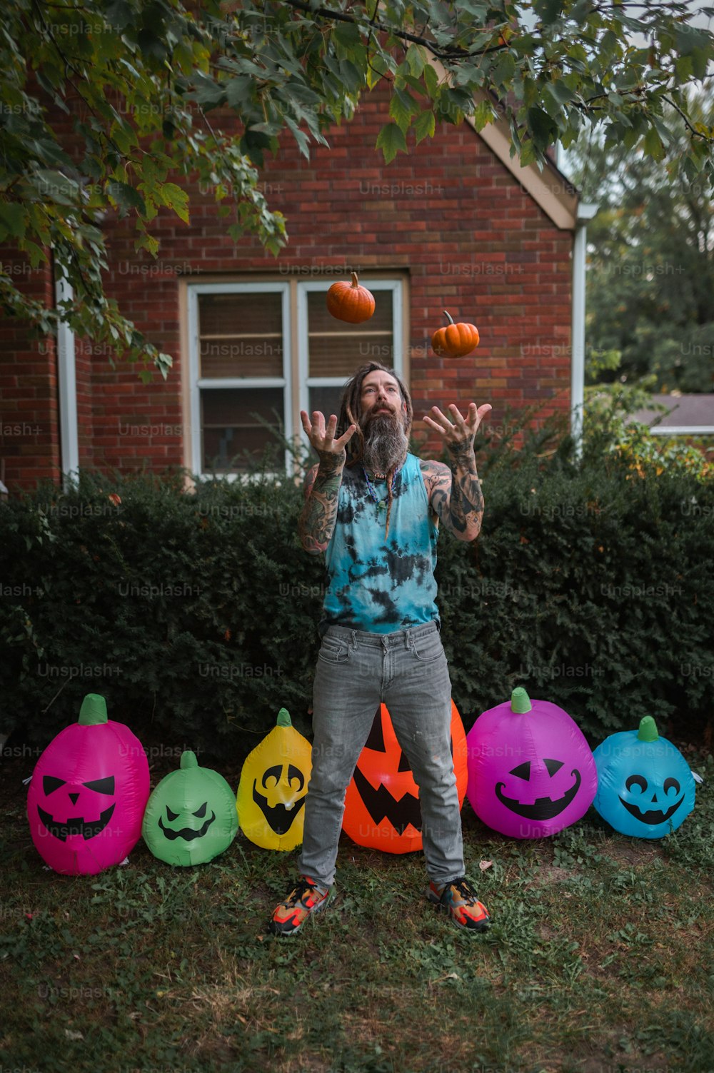 a man juggling pumpkins in front of a house