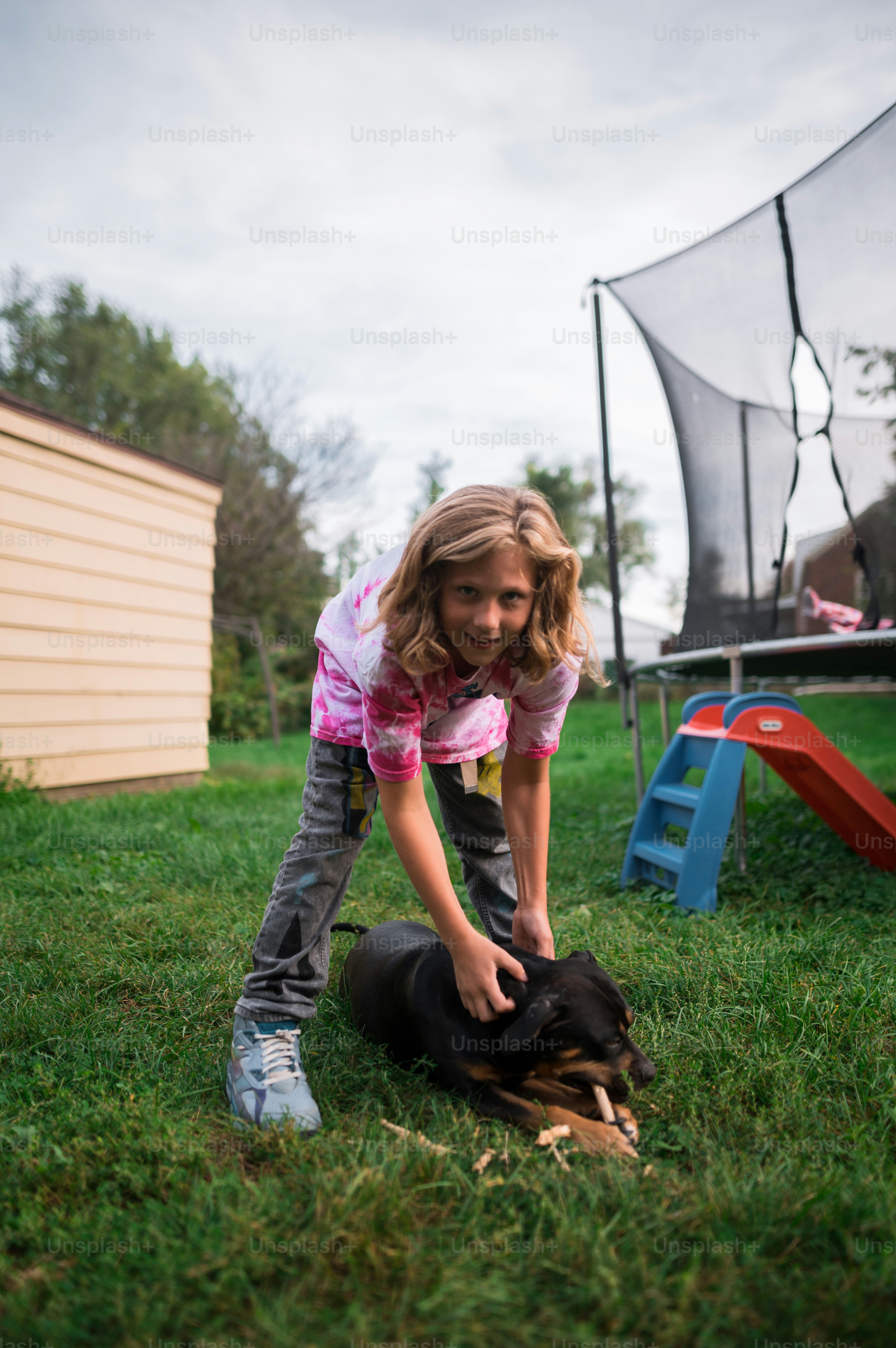 a little girl playing with a dog in the grass