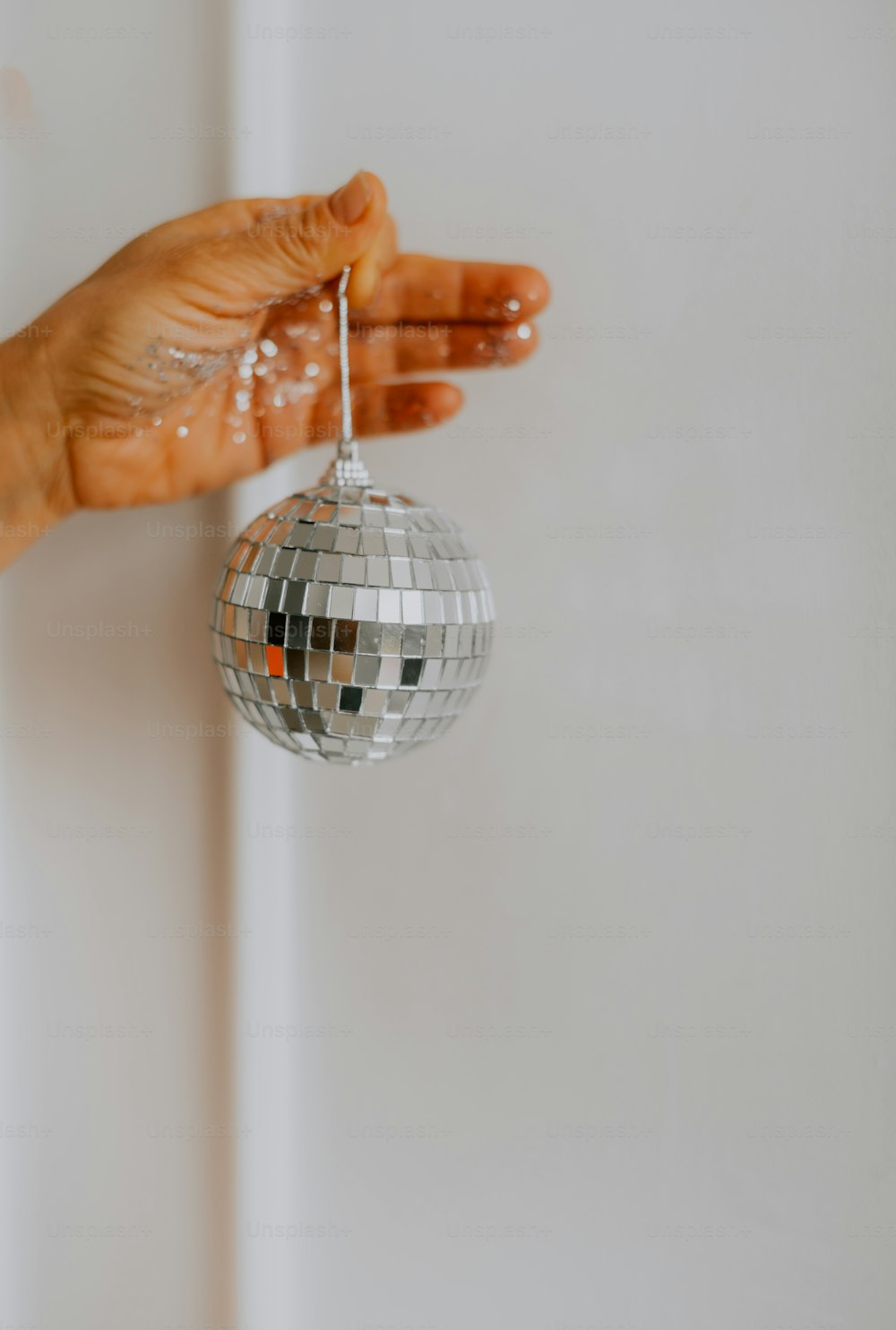 a person's hand holding a disco ball ornament