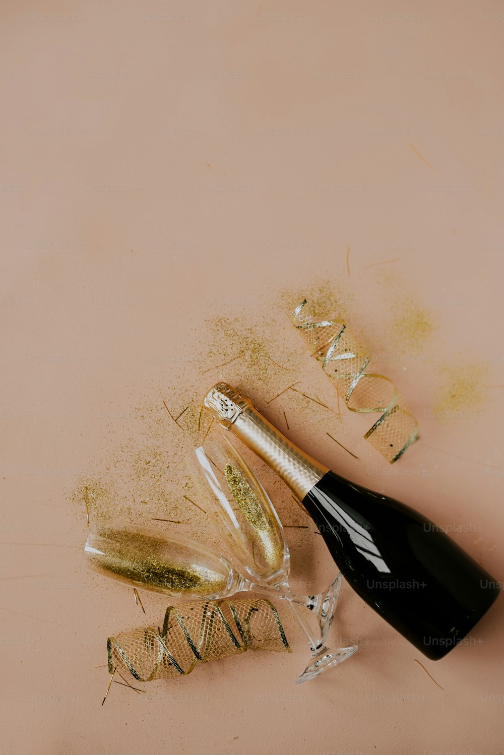 uma garrafa de champanhe ao lado de alguns confetes de ouro