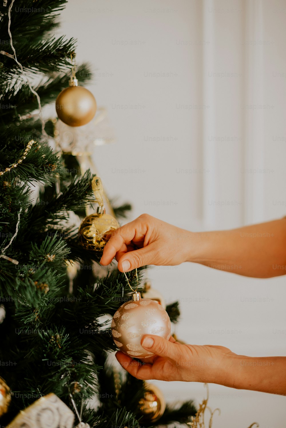 a person decorating a christmas tree with ornaments