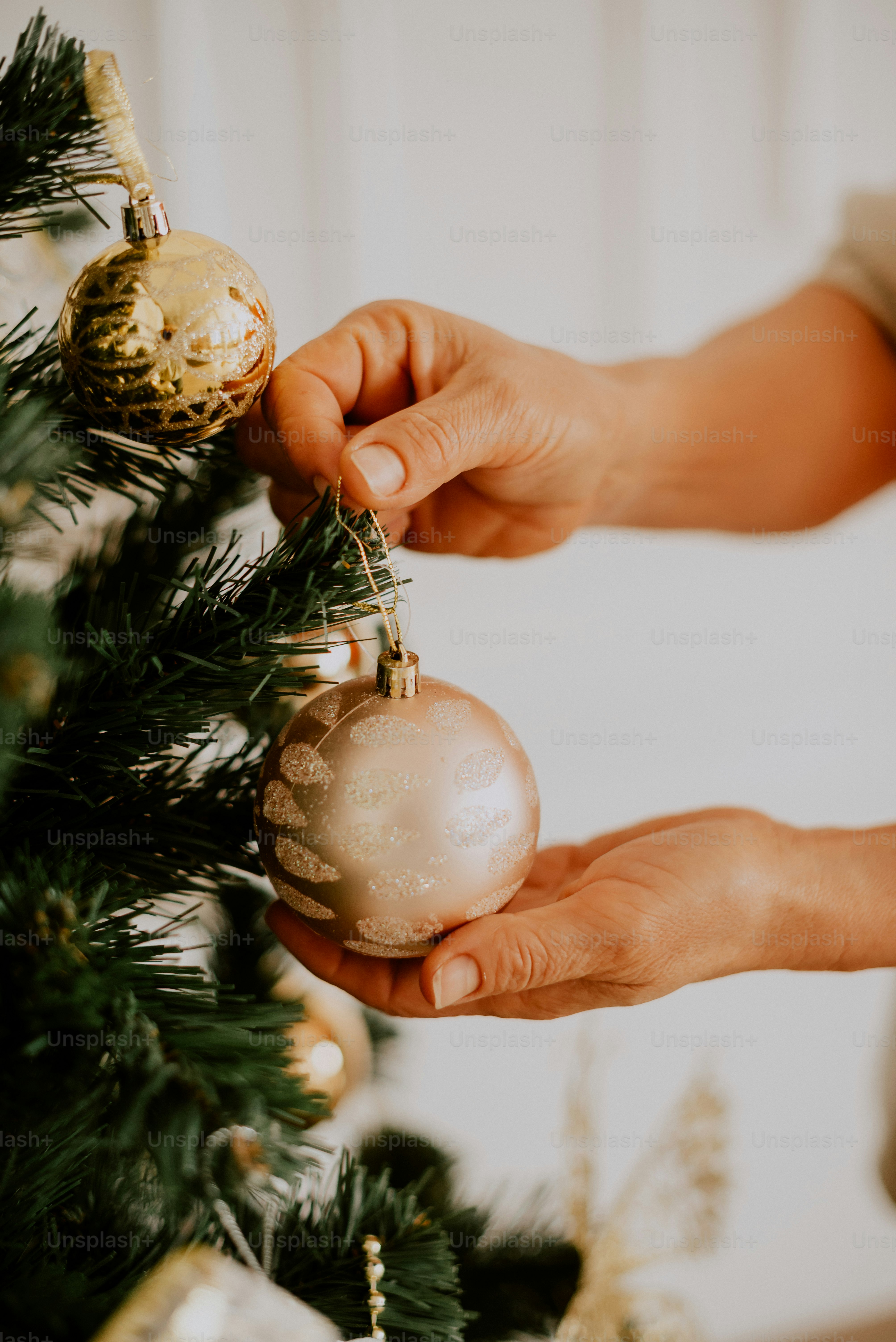 a person decorating a christmas tree with ornaments