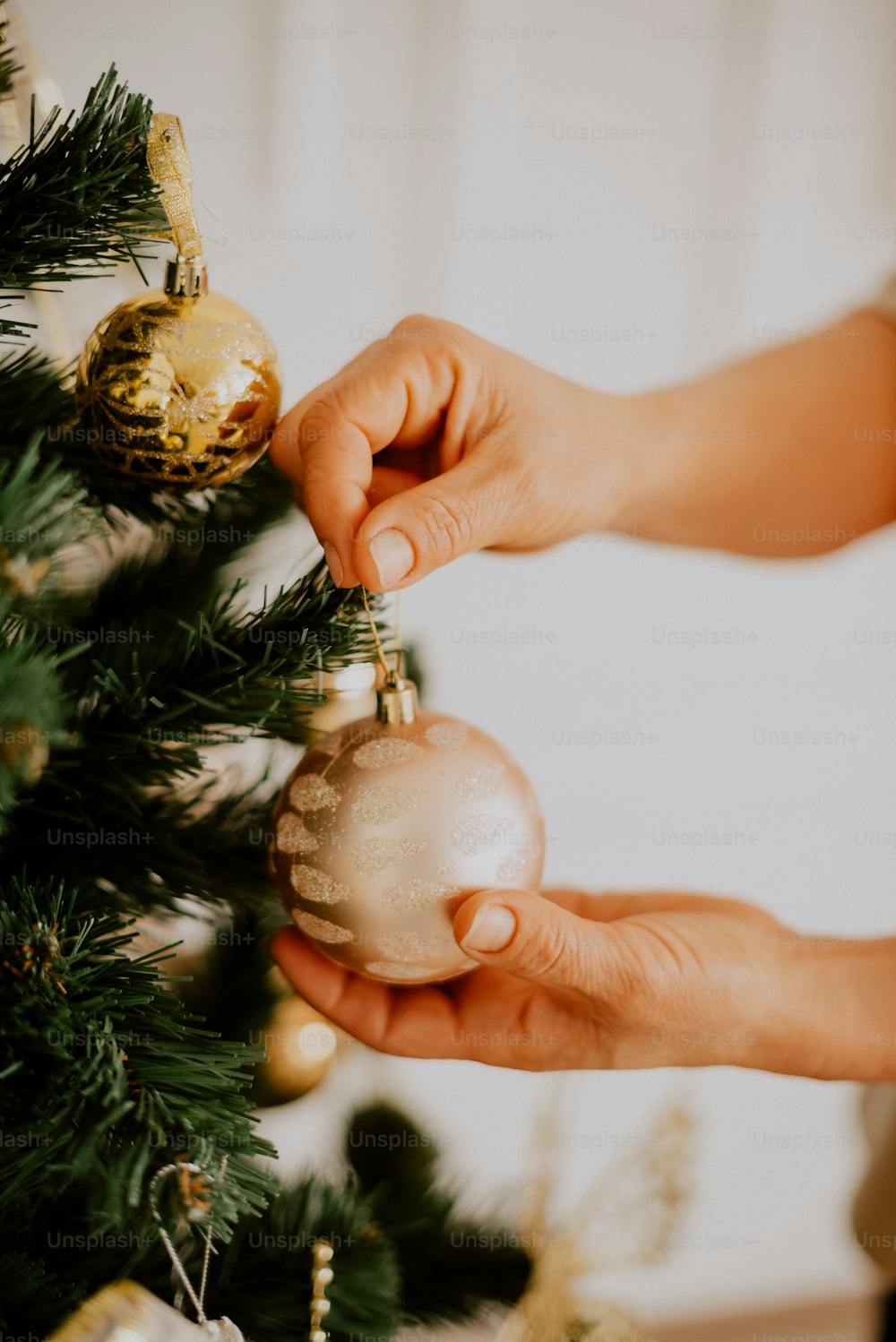 eine Person, die einen Weihnachtsbaum mit Ornamenten schmückt