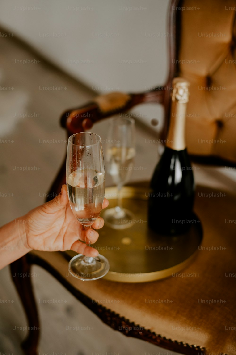 una persona sosteniendo una copa de vino frente a una botella de vino