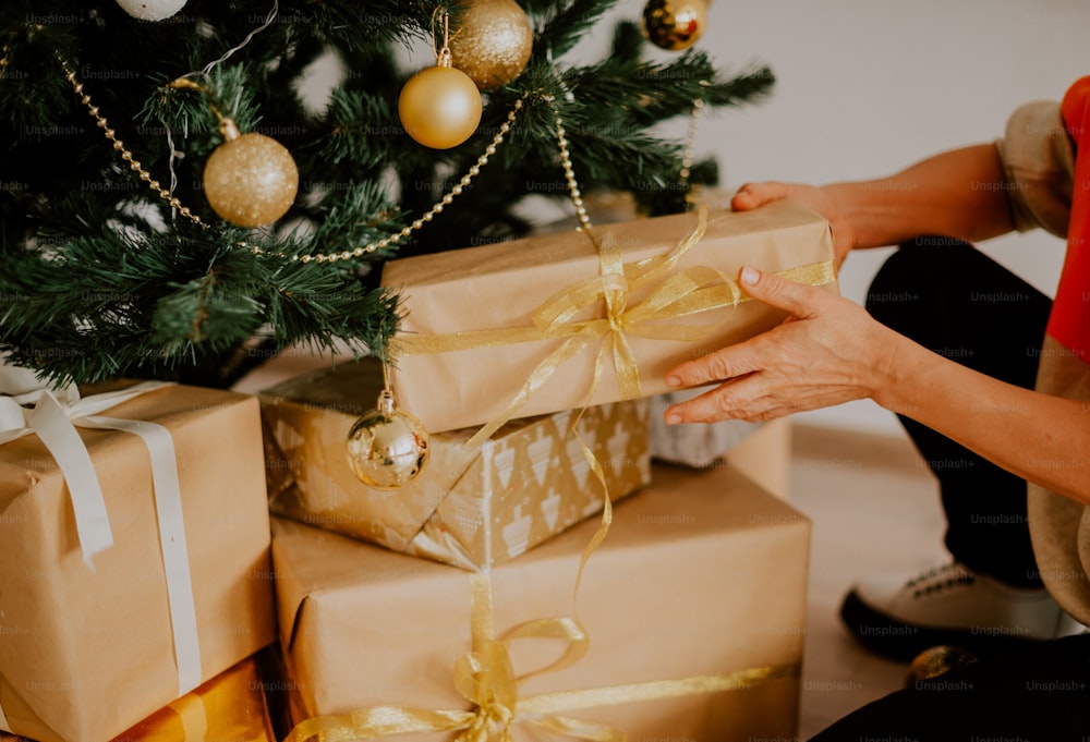 Uma mulher segurando um presente embrulhado perto de uma árvore de Natal