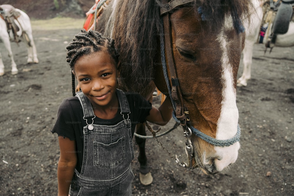 a little girl standing next to a brown and white horse