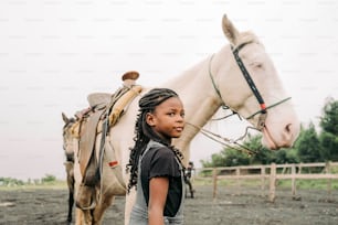 Una niña de pie junto a un caballo blanco