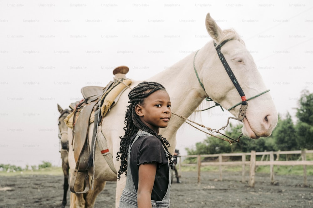 a young girl standing next to a white horse
