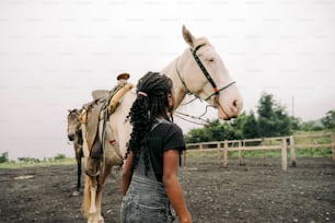 a woman standing next to a white horse