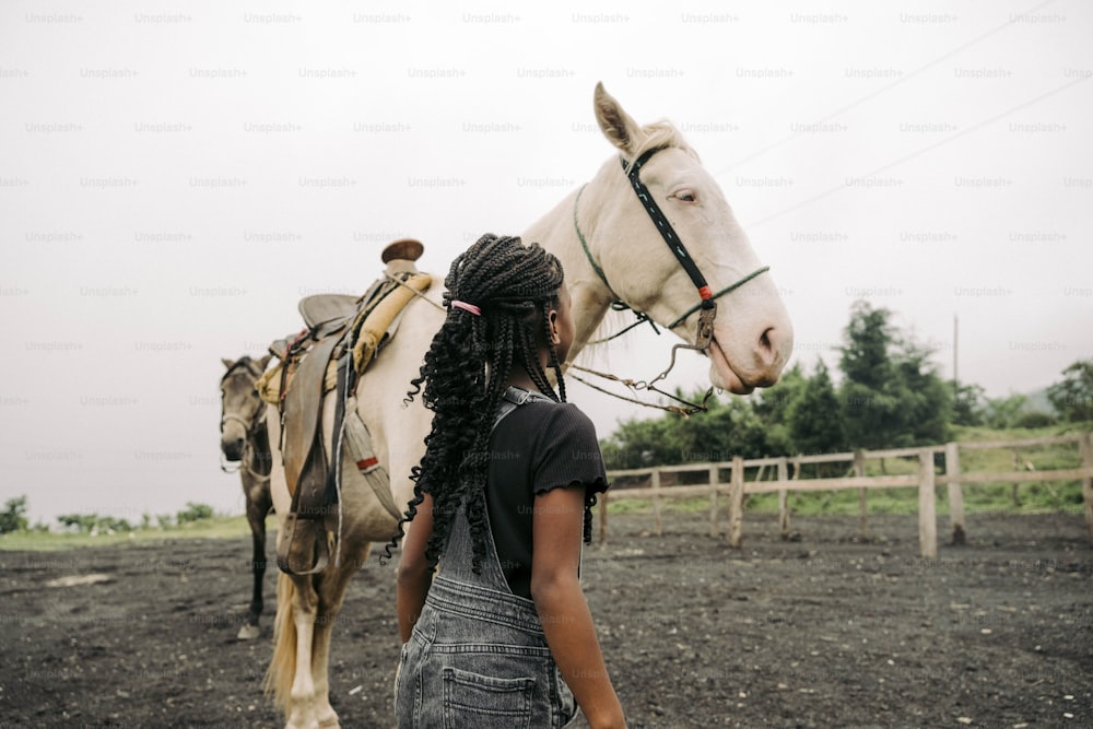 Une femme debout à côté d’un cheval blanc