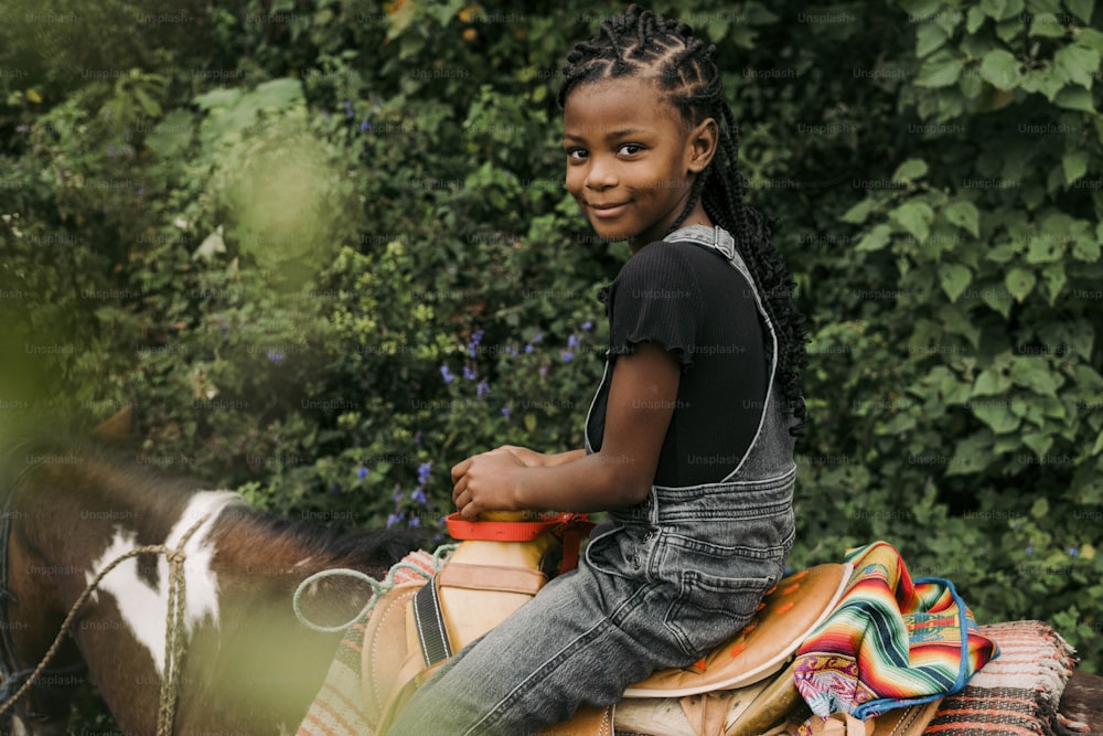 a young girl sitting on a horse in the woods