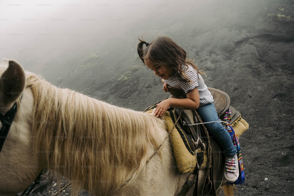 a little girl riding on the back of a white horse