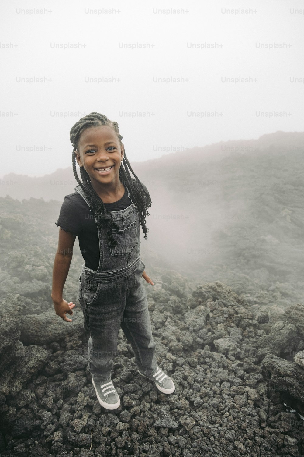 a young girl with braids standing on top of a mountain