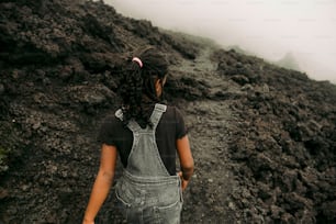 a woman in overalls walking up a hill
