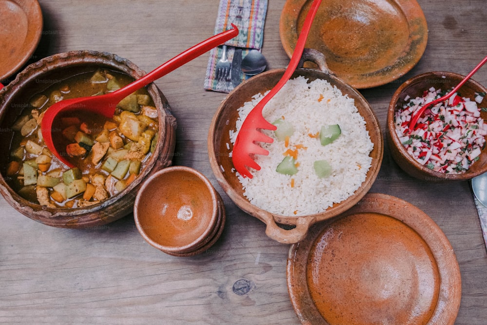 a wooden table topped with bowls filled with food