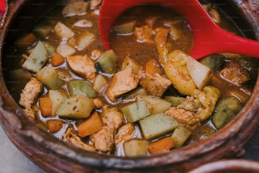 a bowl of stew with a red spoon in it