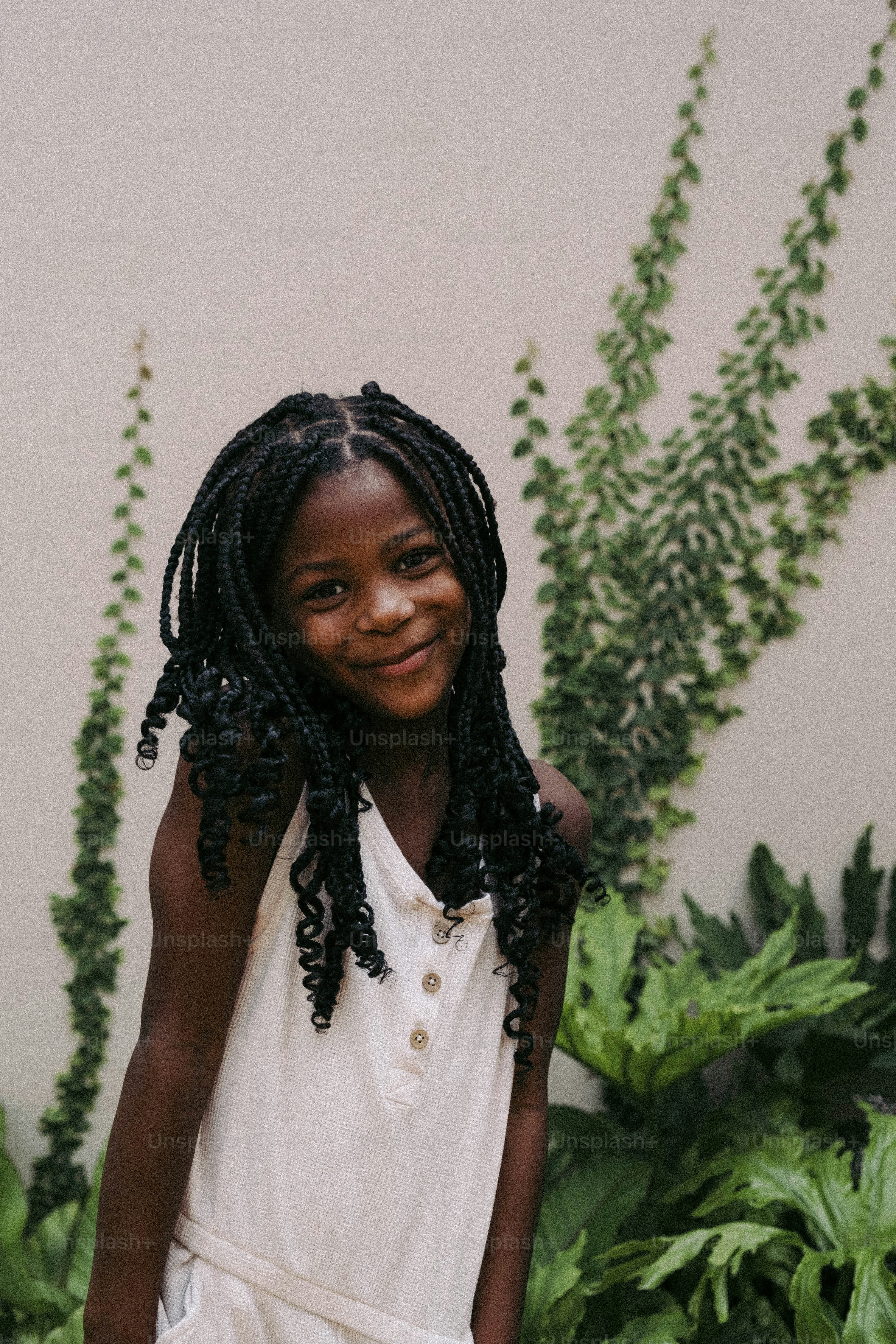 a young girl standing in front of a plant