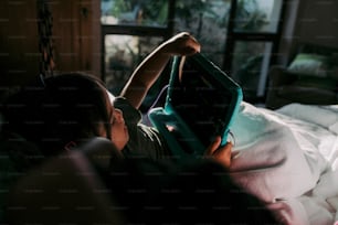 a person laying on a bed with a book in their hand