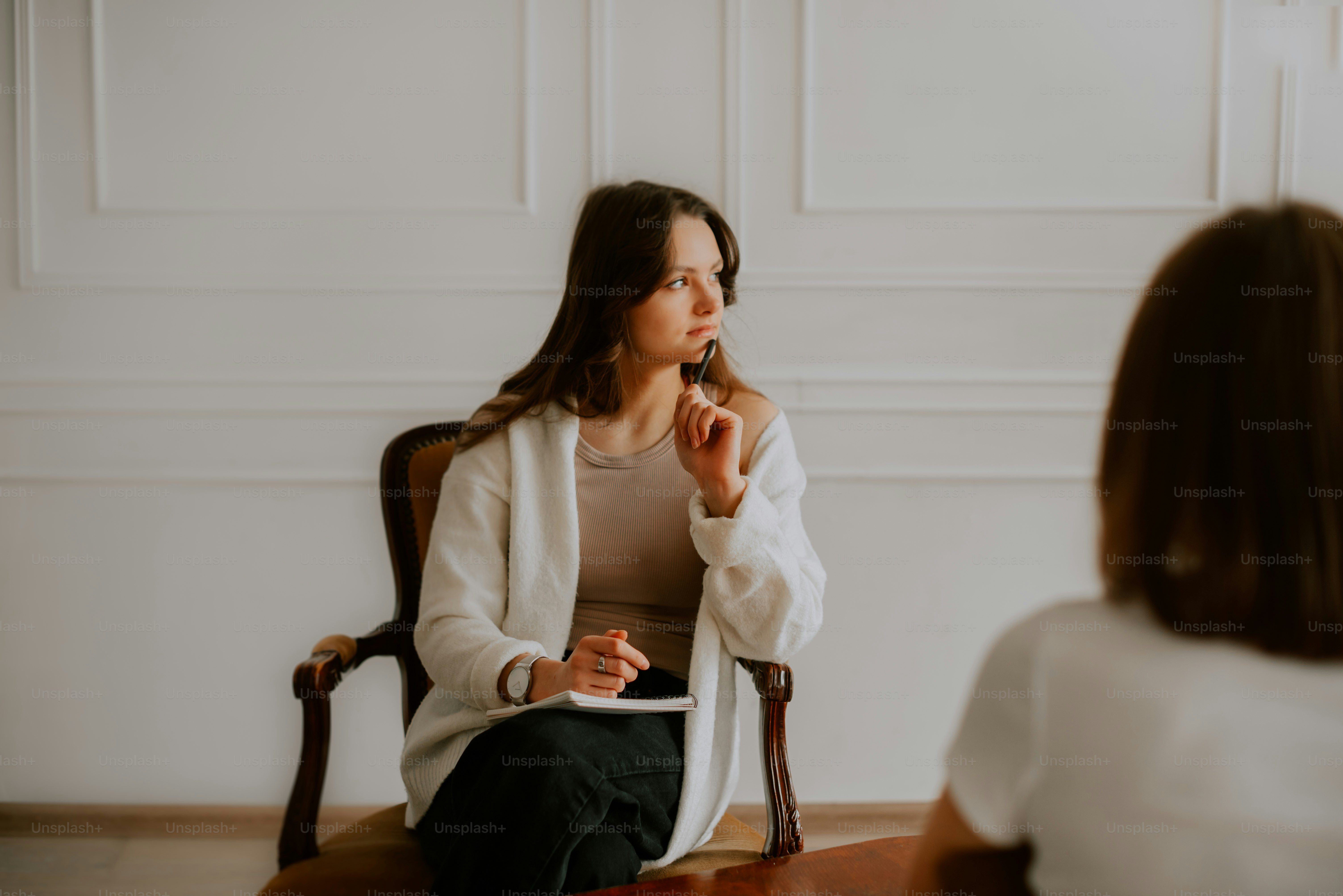 a woman sitting in a chair talking to another woman