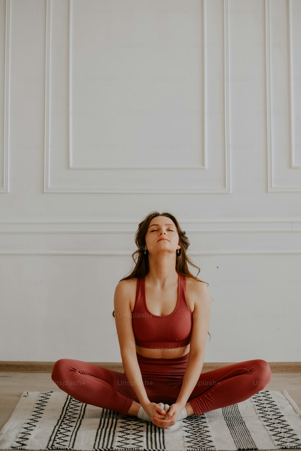 a woman sitting in a yoga pose on a rug