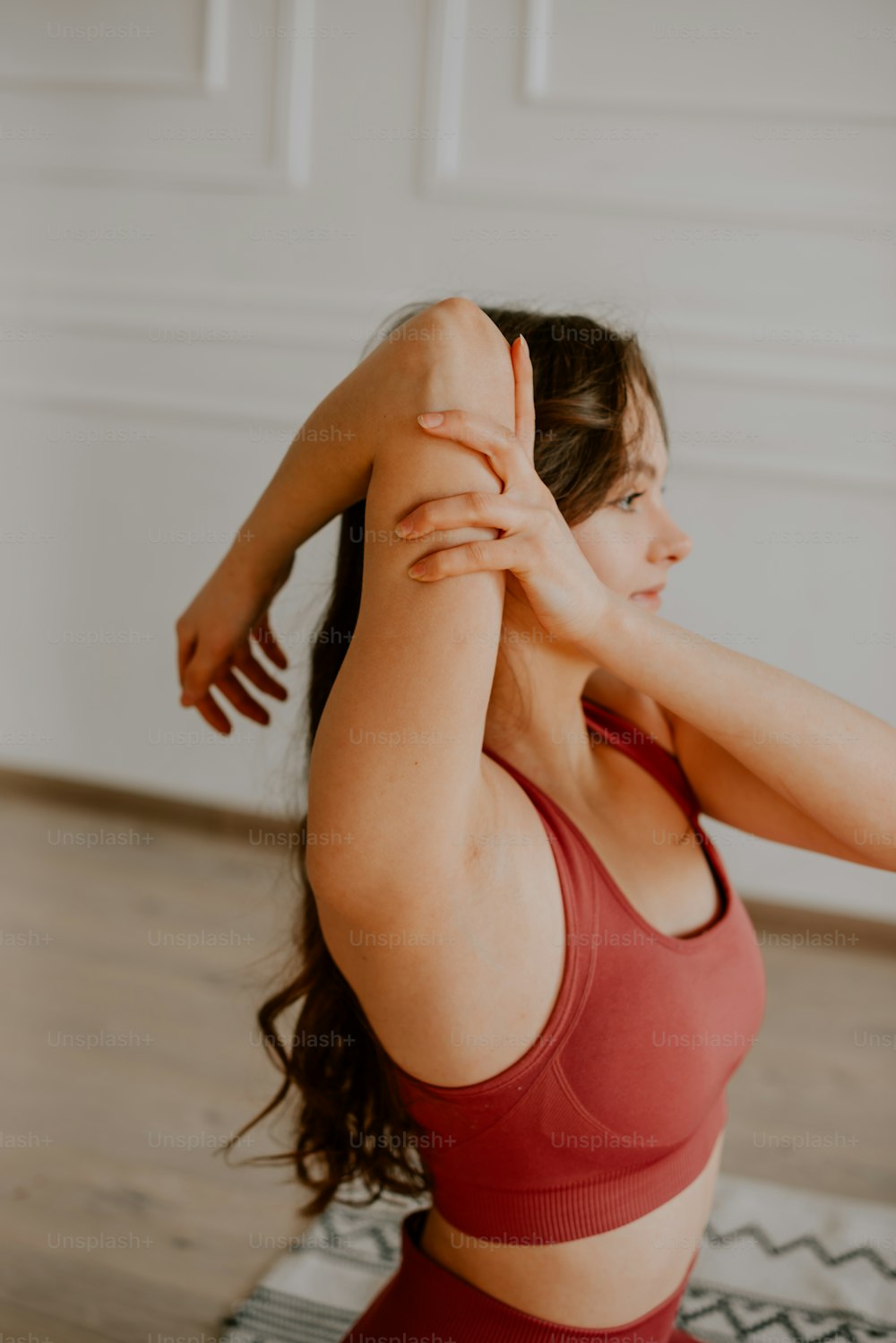 a woman in a red sports bra top stretching her arms