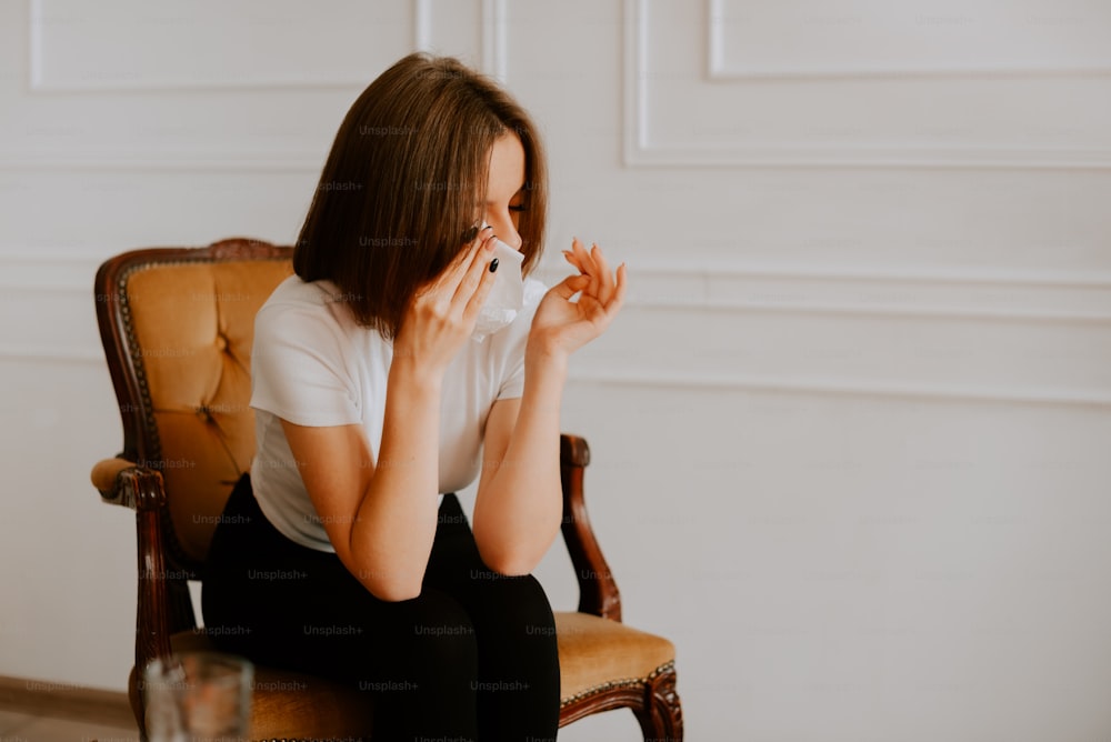 a woman sitting in a chair with a tissue in her hand