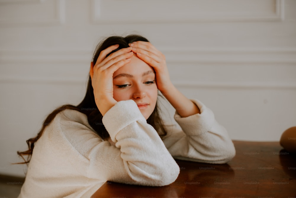 a woman sitting at a table with her hands on her head