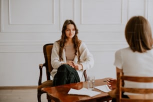 a woman sitting in a chair talking to another woman