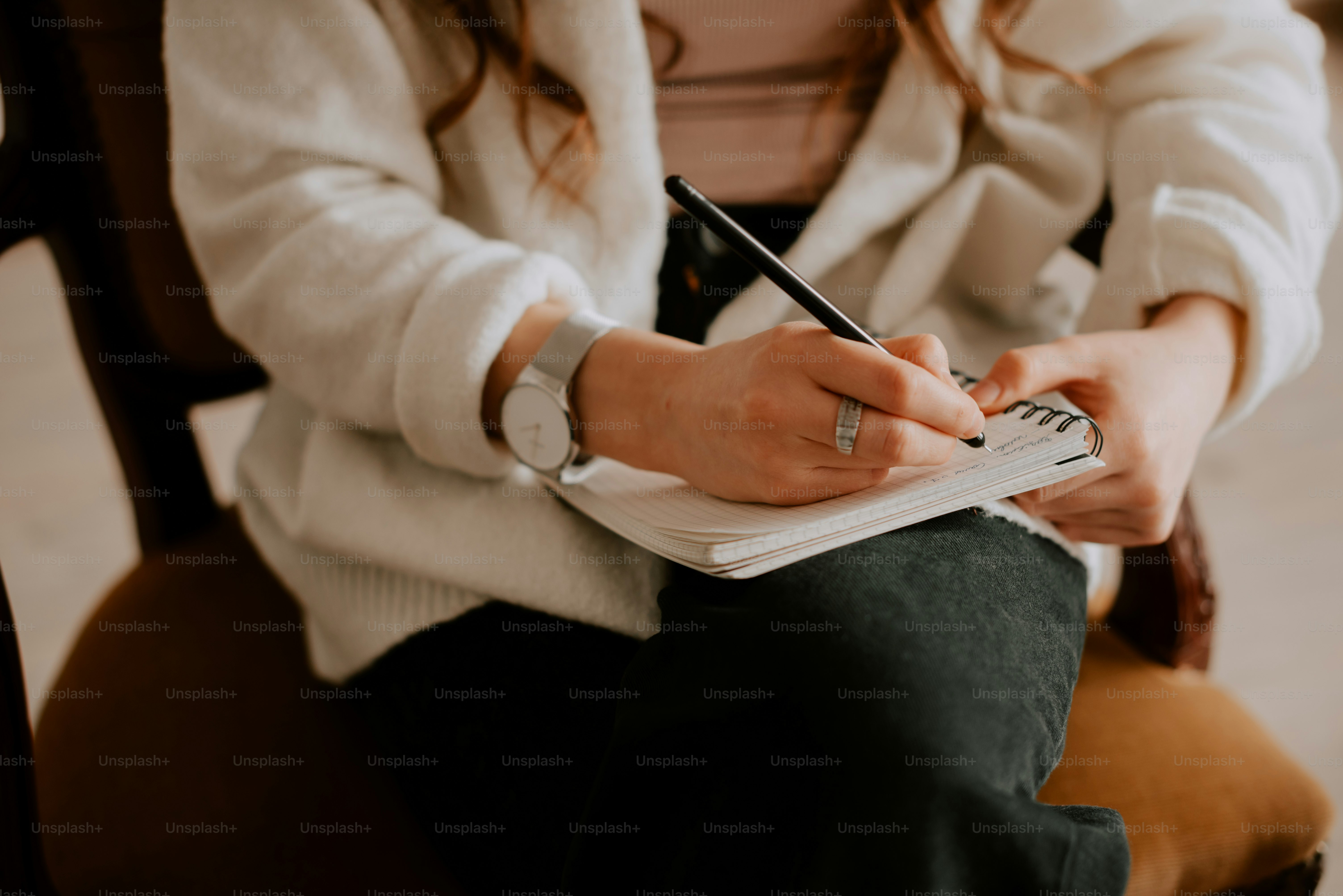 a woman sitting in a chair writing on a notebook