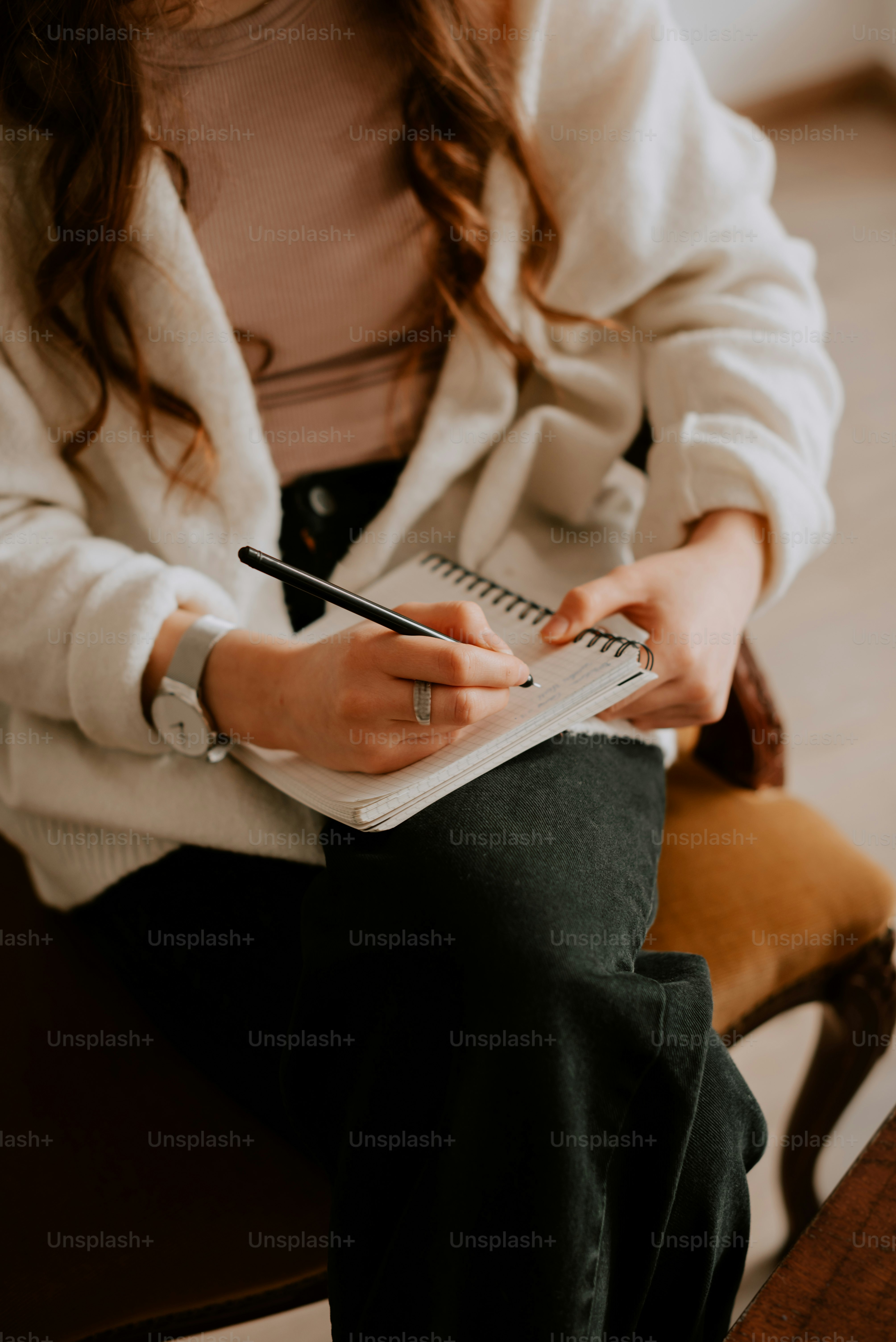 a woman sitting on a chair writing on a notebook